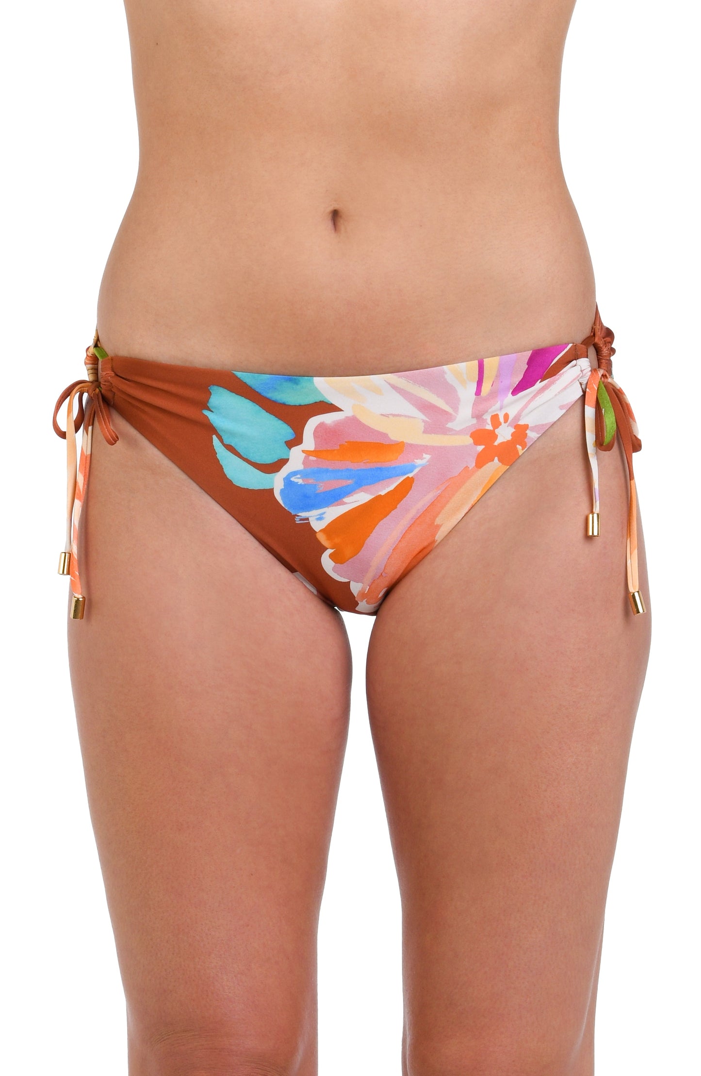 Model is wearing floral patterned swimsuit bottom with bold strokes of peach, pink, orange, and blue hues on a rich brown background.