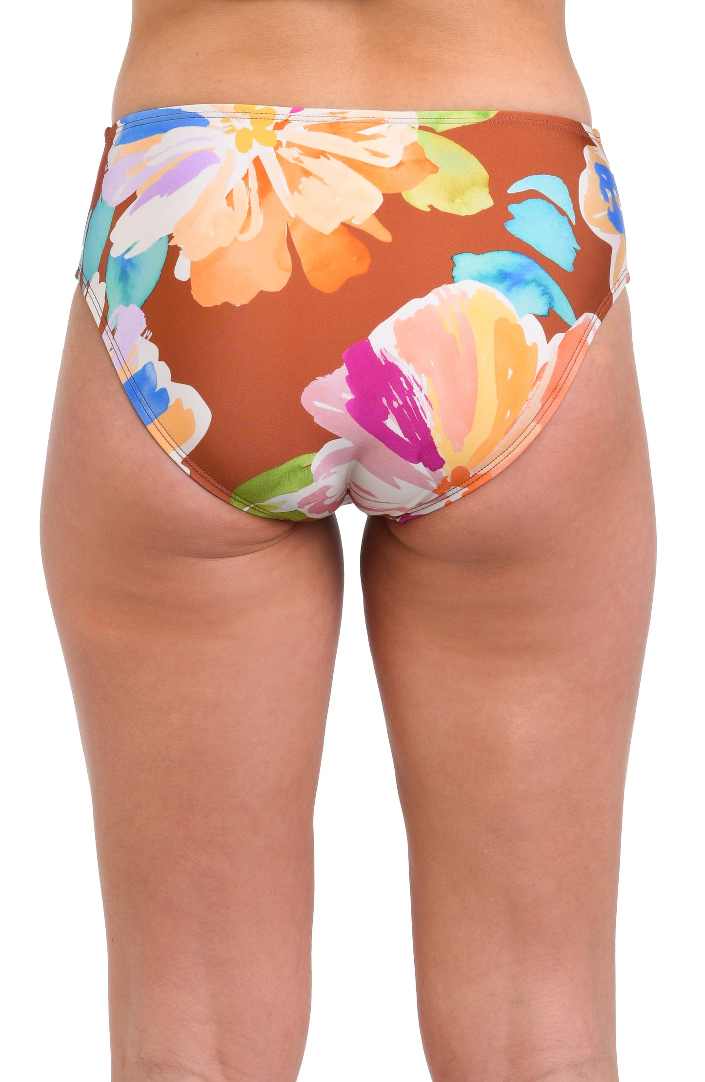 Model is wearing floral patterned swimsuit bottom with bold strokes of peach, pink, orange, and blue hues on a rich brown background.