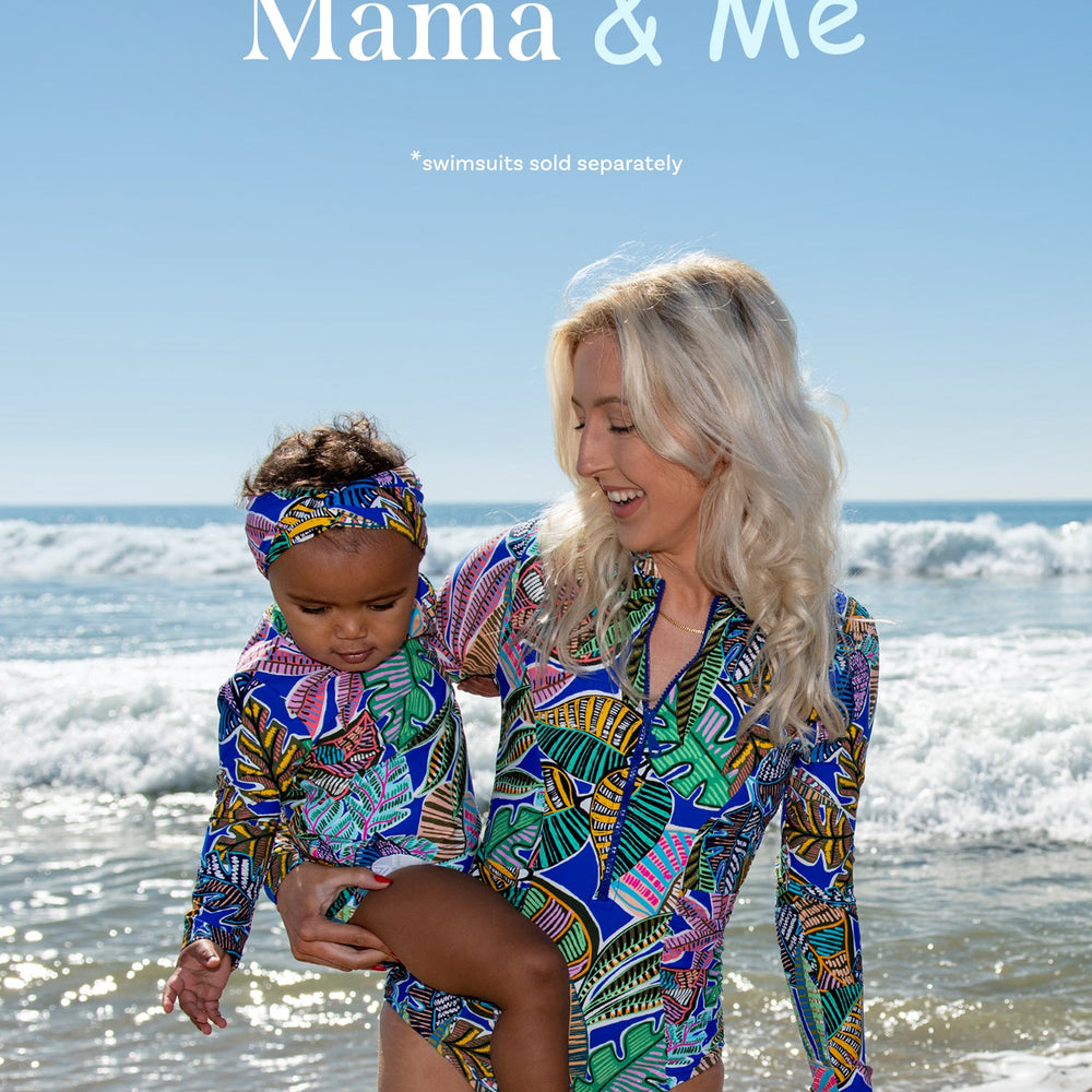 Toddler is wearing a neon colored tropical printed long sleeve rashguard top and hipster bottom set from our Mama and Me Neon Nights collection.