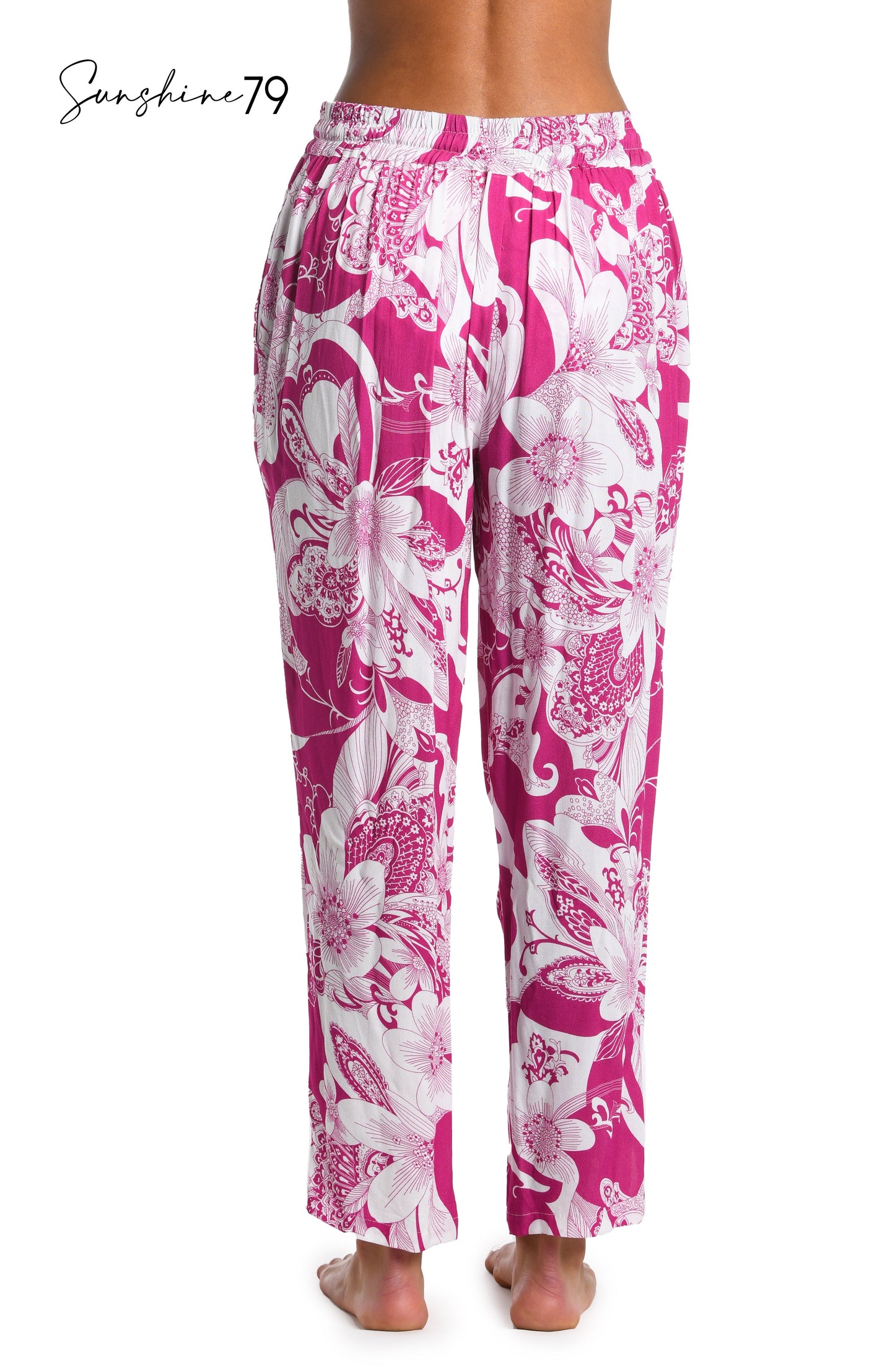 Model is wearing a fuchsia and white multicolored tropical printed beach pant cover up from our Sunshine 79 brand.